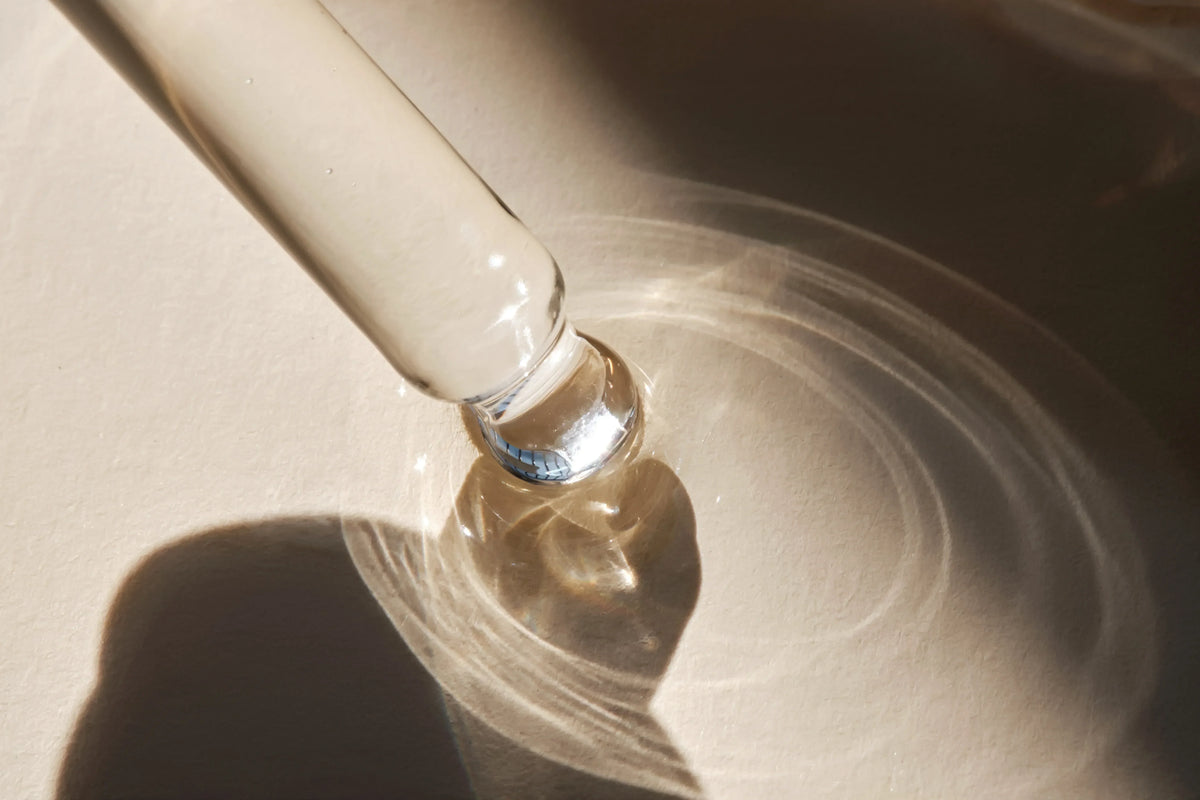 Dropper releasing active skincare serum with light reflections, symbolizing precision formulation and ingredient purity